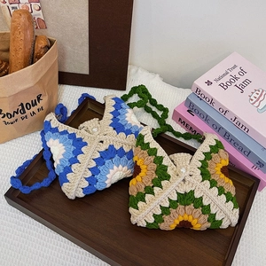 Handmade crochet sunflower tote bag with floral patterns on a wooden tray with books