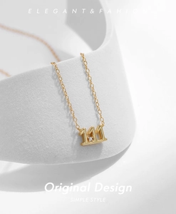 Detail of gold 111 pendant necklace with sparkling stone on elegant white display stand