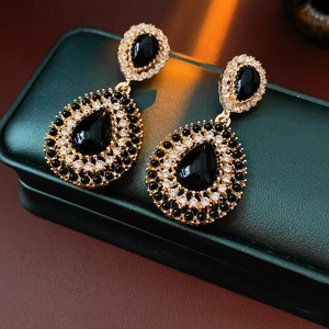 Détail de boucles d'oreilles vintage dorées avec cristaux noirs et faux diamants