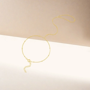 Detail of delicate gold bead finger bracelet with adjustable chain and spring clasp
