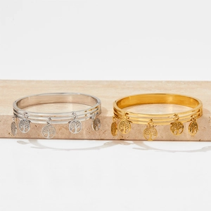 Polished gold and silver stainless steel layered tree of life bracelets on marble