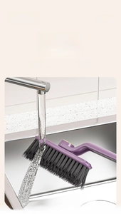 Macro shot of long-handle crevice cleaning brush being rinsed under running water in a sink