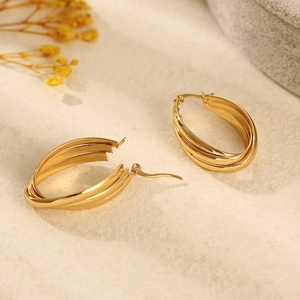 Boucles d'oreilles ovales triples en acier inoxydable doré sur fond texturé élégant