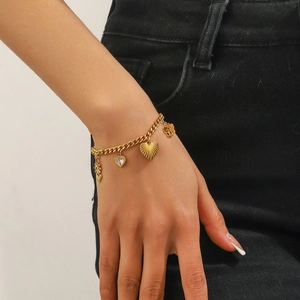Detail view of gold-plated chain bracelet with daisy and heart charms on a person's wrist