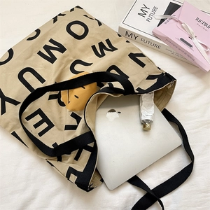 Canvas tote bag with alphabet print showing large capacity for laptop storage