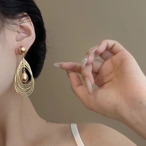 Close-up of layered gold teardrop earrings worn by model for an elegant luxury style