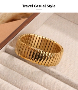 Close-up of golden wide stretch tubogas bracelet on a beige linen jewelry display tray