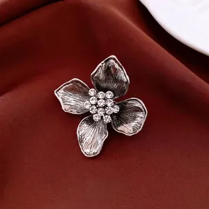 Vintage silver flower brooch with crystal center and brushed petals on red silk fabric