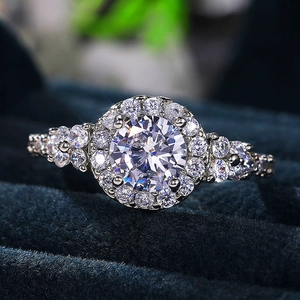 Macro shot of a halo-style round zircon engagement ring on a blue velvet jewelry box