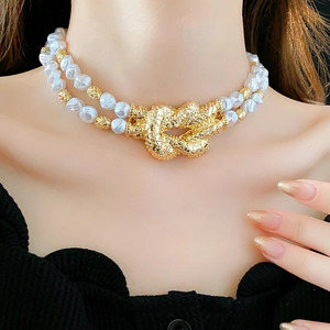 Macro detail of French style double-layer pearl necklace with a textured golden knot buckle