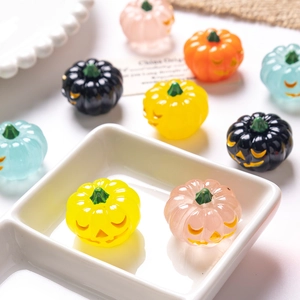 Close-up of colorful mini Halloween pumpkin resin figurines scattered on a white tray