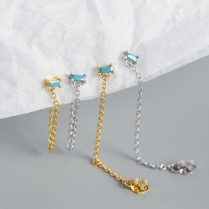 Macro detail of gold and silver S925 tassel chain earrings with turquoise cubic zirconia
