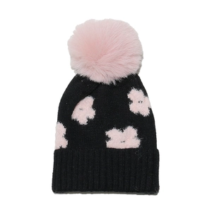 Close-up of winter knit hat featuring pink floral patterns and a fluffy faux fur pom-pom