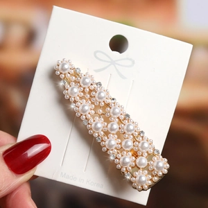 Macro detail of elegant pearl hair clip with sparkling rhinestones on golden base