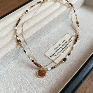 Detail of 18K gold plated tiger eye necklace with double-layer beads on jewelry tray