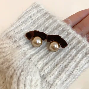 Vintage flocked bow earrings with champagne pearls on white knitted sweater sleeve