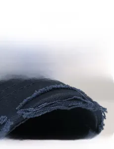 Detailed close-up of distressed ripped edges on a dark navy cotton baseball hat brim