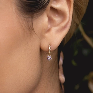 Close-up of gold S925 sterling silver hoop earrings with purple flower pendant and crystals