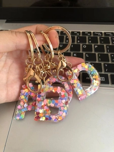 Detail of A, B, D resin alphabet keychains with colorful heart sequins and gold hardware