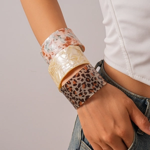 Close-up of three wide acrylic bangles in pink marble, pearl white, and leopard print