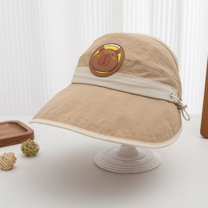 Detail of khaki sun visor for kids with bear patch and capibara text on a white stand