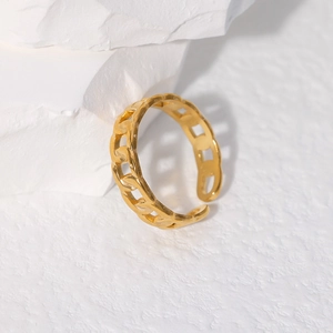 Detailed close-up of a minimalist gold chain-style open ring on white artistic stone