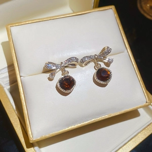 Macro shot of bowknot earrings with brown round pendants in a golden jewelry box
