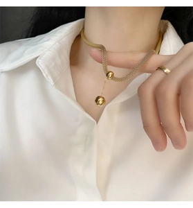 Dettaglio ravvicinato di una collana choker dorata a trama con pendente a sfera