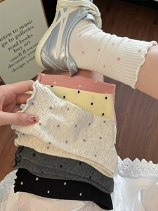 Polka dot crew socks with ruffled cuffs shown in multiple colors on a wooden floor