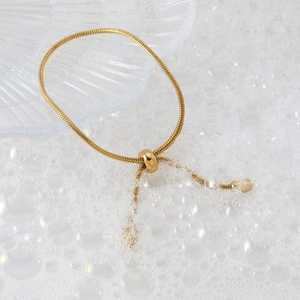 Elegant gold snake chain bracelet with adjustable sliding clasp on shell tray