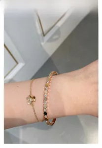 Close-up of gold honeycomb bangle and clover bracelet with diamonds on woman's wrist