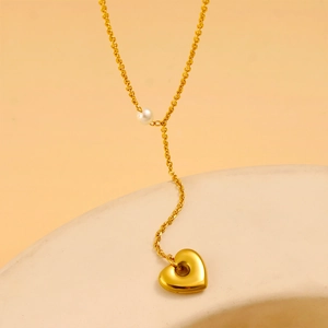 Detail of gold heart pendant necklace with white pearl on a Y-shaped chain