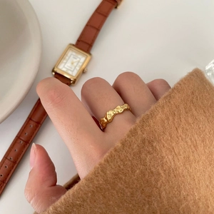 Minimalist irregular lava texture gold ring for women shown on a model hand with accessories