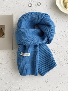 Dettaglio della sciarpa in maglia spessa blu reale con etichetta in stile vintage