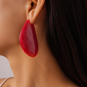 Gros plan d'une grande boucle d'oreille rouge en résine de forme organique irrégulière
