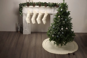 White knitted Christmas stockings hanging on fireplace with festive tree and mantel decor