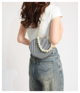 Detailed view of grey glitter shell bag with gold chain and large pearl bead handle