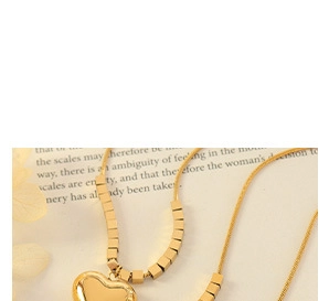 Detail of a golden heart pendant necklace with a box chain on an open vintage book page