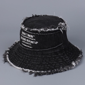 Dettaglio del ricamo bianco e dei bordi sfrangiati su un cappello a secchiello in denim