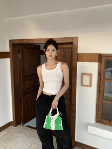 Detail of green and white handmade crochet bag with floral pattern held by a model