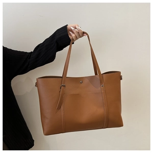 Close-up of brown PU leather tote bag with slender straps and front pocket detail