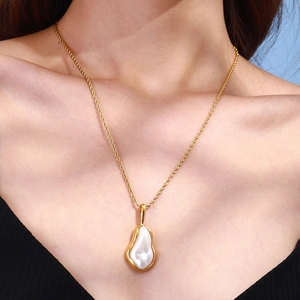 Elegant gold twisted chain necklace with a white baroque pearl pendant worn by a model