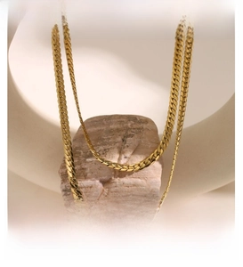 Detail of double-layered 18k gold plated titanium steel cuban link chains on stone decor
