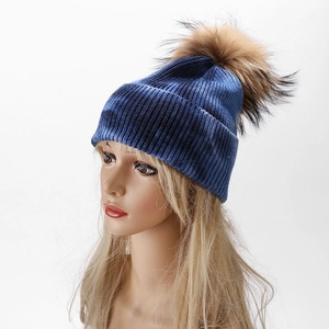 Detail of blue tie-dye ribbed knit beanie with a large brown faux fur pom-pom topper