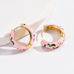 Macro shot of gold-plated enamel hoop earrings featuring delicate floral patterns