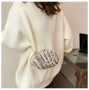 Close-up of silver leaf-shaped evening bag with pleated texture and pearl handle accessory