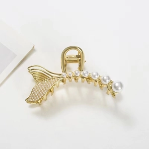 Detailed view of elegant gold fishtail hair claw clip with multiple white pearls