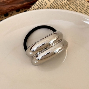 Close-up of minimalist hair tie with silver geometric metal tubes on black elastic cord