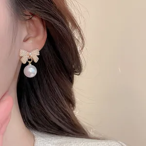 Close-up of elegant bow pearl earring with gold metal and micro pearl inlay on model