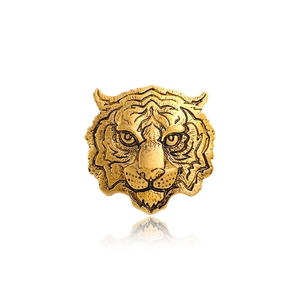 Detailed golden tiger head brooch in vintage style with relief texture on white background